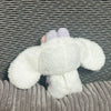A white, fluffy rabbit costume with pink ears is displayed against a striped background.