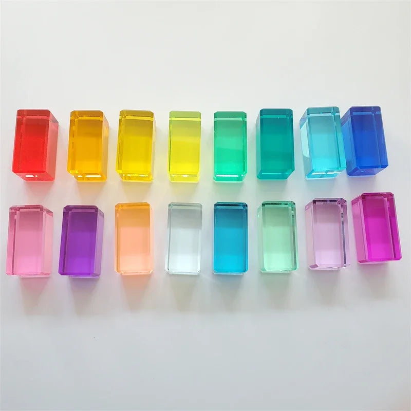 A collection of colorful, translucent acrylic building blocks in various shades of rainbow colors arranged in a row.