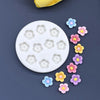 A white silicone mold with multiple daisy flower shapes in various pastel colors, arranged around the edge.