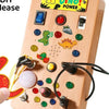 A wooden busy board featuring various interactive elements like switches, knobs, and buttons for children's learning.