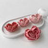 Pink heart-shaped flower silicone molds arranged on a white tray with a white sphere.