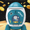 A white and blue rocket shaped piggy bank with a key lock is shown on a sandy surface surrounded by gold coins.