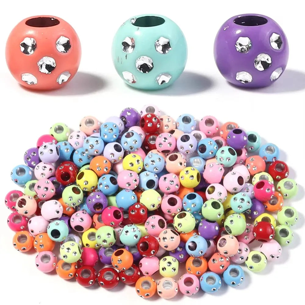 A collection of colorful, iridescent rhinestone acrylic spacer beads in various shades of pink, purple, and green.
