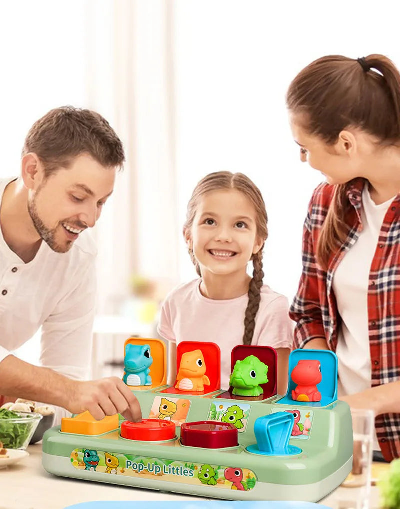 A girl and a man interact with a green pop-up animal toy set for cause and effect learning.