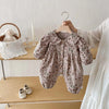 A floral print baby girl long sleeve jumpsuit with a collar is displayed on a hanger.
