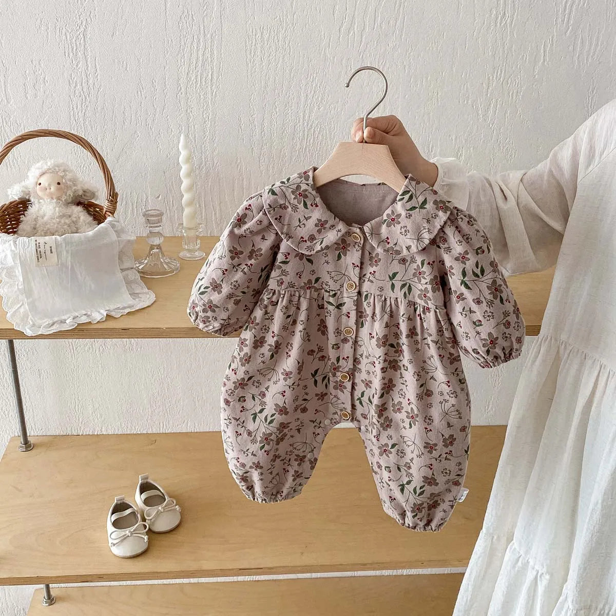 A floral print baby girl long sleeve jumpsuit with a collar is displayed on a hanger.