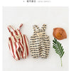 A striped baby romper with bear decoration displayed next to a solid brown hat and green leaves.