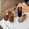 A pair of girls' brown moccasins with bow details and suede accents resting on a white cloth.