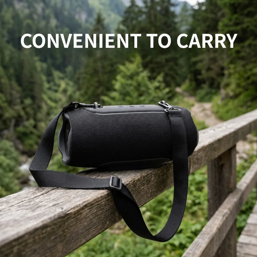Black portable Bluetooth speaker with a strap resting on a wooden railing in a forest setting.