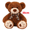 A brown teddy bear plush pillow with a plaid bow and visible stitching details.