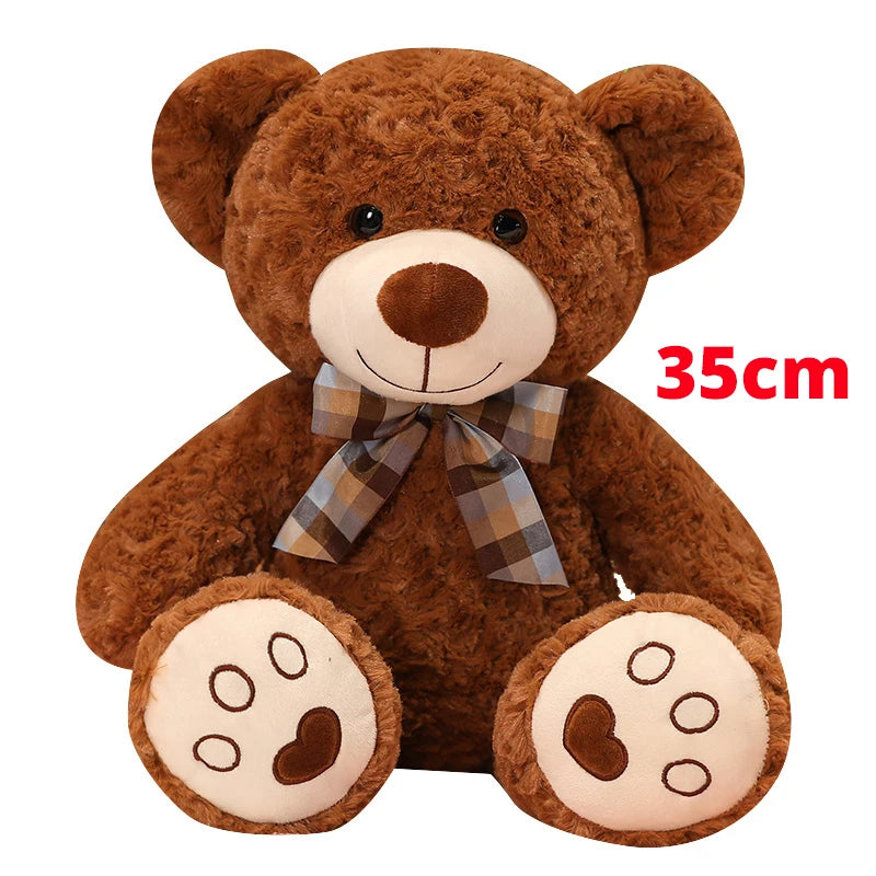 A brown teddy bear plush pillow with a plaid bow and visible stitching details.