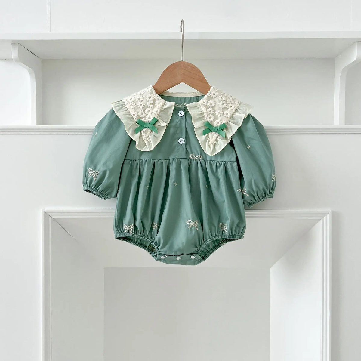 A teal cotton party dress for girls featuring white lace collar details and embroidered accents, displayed on a hanger.