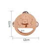 A round wooden bear musical instrument with a cutout for a toddler, featuring a cute bear design and small leaves.
