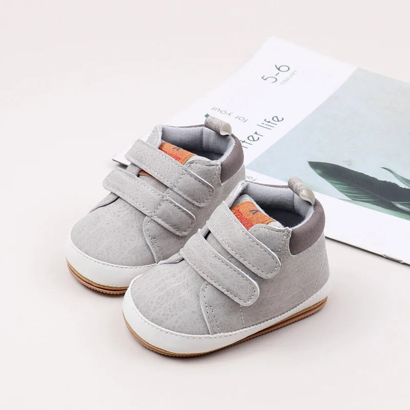 A pair of soft gray baby first walker shoes with anti-slip sole resting on a white background.