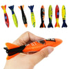 A hand holds an orange shark rocket pool diving toy alongside several colorful shark toys.