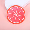 A round, sliced orange fruit pattern coaster with white lines rests on a pink surface next to a white box.