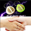 A hand buzzer toy with a gold ring and a green plastic body is shown against a background of lightning.