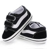 A pair of black and white striped canvas sneakers for babies shown from the side.