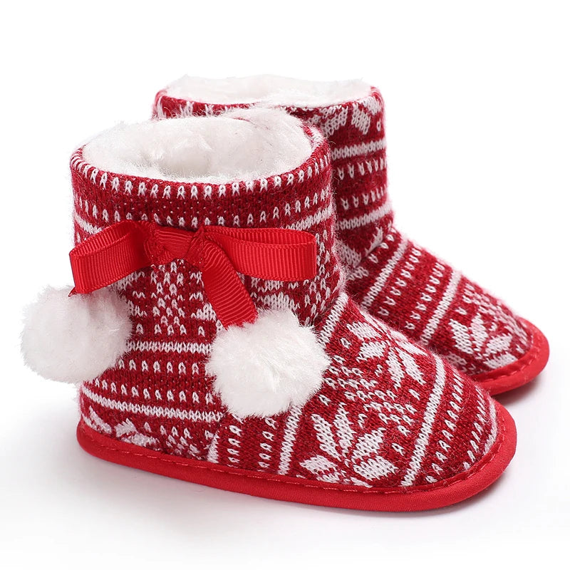 Pair of red knitted baby first walker shoes with white faux fur trim and a red bow