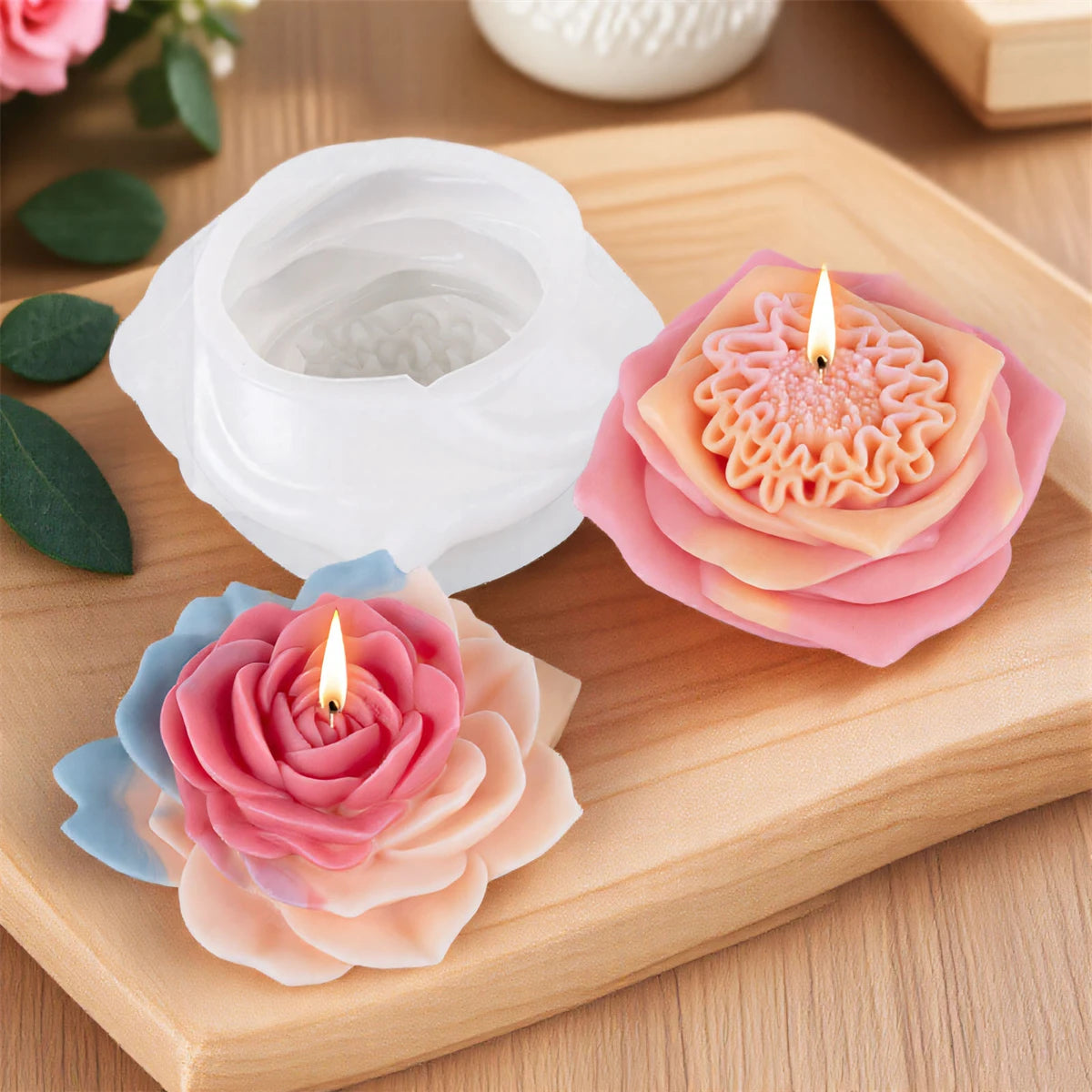 Pink and peach silicone candle molds with lit candles displayed on a wooden board