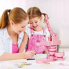 Two girls are using a pink multi-size button making machine kit to create buttons.