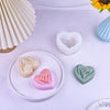 A collection of heart-shaped silicone molds in various pastel colors, including white, pink, and green, displayed on a white 