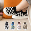 A collection of classic plaid slip-on toddler shoes for first walkers in various colors and patterns.