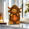 A fluffy brown Highland cow plush toy with lighted features sitting on a windowsill.
