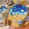 A vibrant blue and yellow ocean-themed silicone baking mold set featuring a decorated cake and various molds.