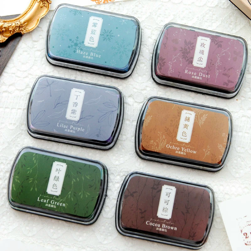 A collection of vintage craft oil-based ink pads in various colors including haze blue, rose dust, lilac purple, ochre yellow
