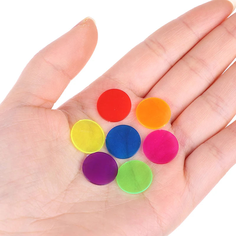 A hand holds a set of seven colorful plastic bingo chips in various shades including red, orange, yellow, blue, purple, and g
