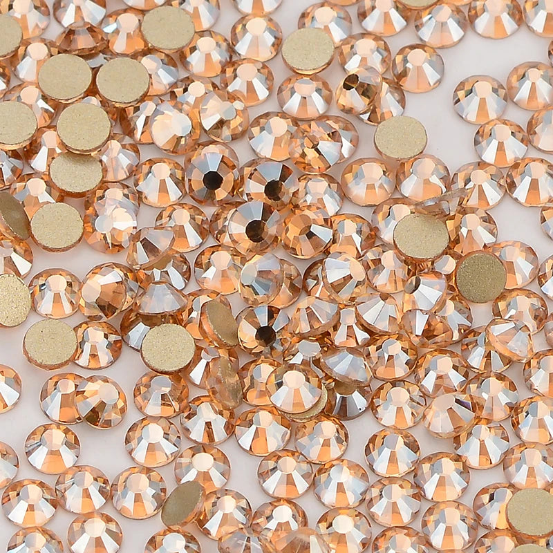 A close-up view of small, round glass crystal flatback rhinestones in shades of gold and amber.