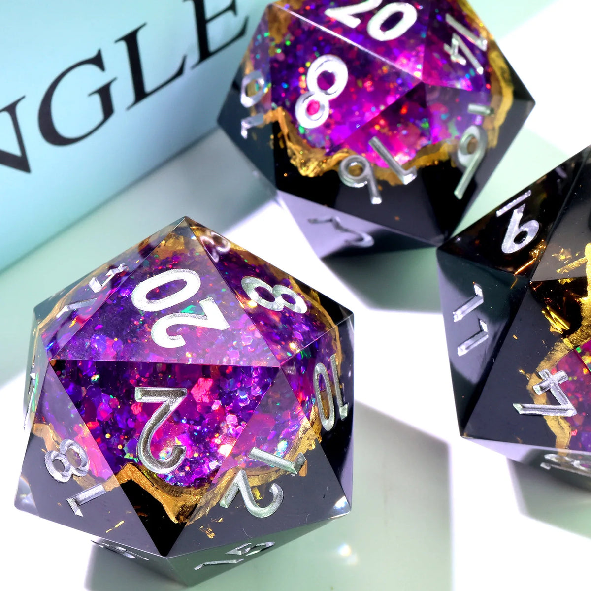 A handmade resin D20 die with a large blue and purple liquid swirl inside.