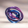 A close-up of a 3D printed rainbow spinner ring with iridescent purple and blue bands, shown in a circular motion.