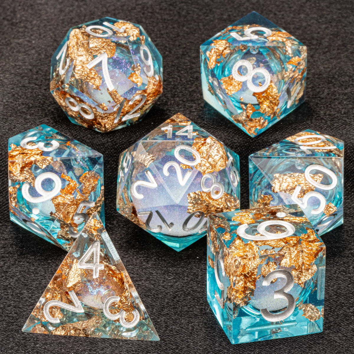 A set of liquid core dice including a d6, d8, d10, d20, and d30 in various shades of blue and gold.
