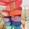 A colorful sensory music tree with a marble run is shown, featuring stacked wooden discs in various shades of pink, orange, p