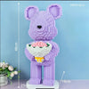 A purple flower bear figure made of micro building blocks standing on a white base.