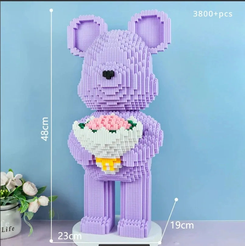 A purple flower bear figure made of micro building blocks standing on a white base.