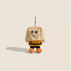 A tan plush charm resembling a character with a large head and yellow body, hanging from a chain.