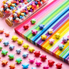 A colorful assortment of origami star strips in various colors laid out on a pink surface.