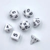 A collection of seven mini polyhedral dice, including d6s and d8s, scattered on a white surface.