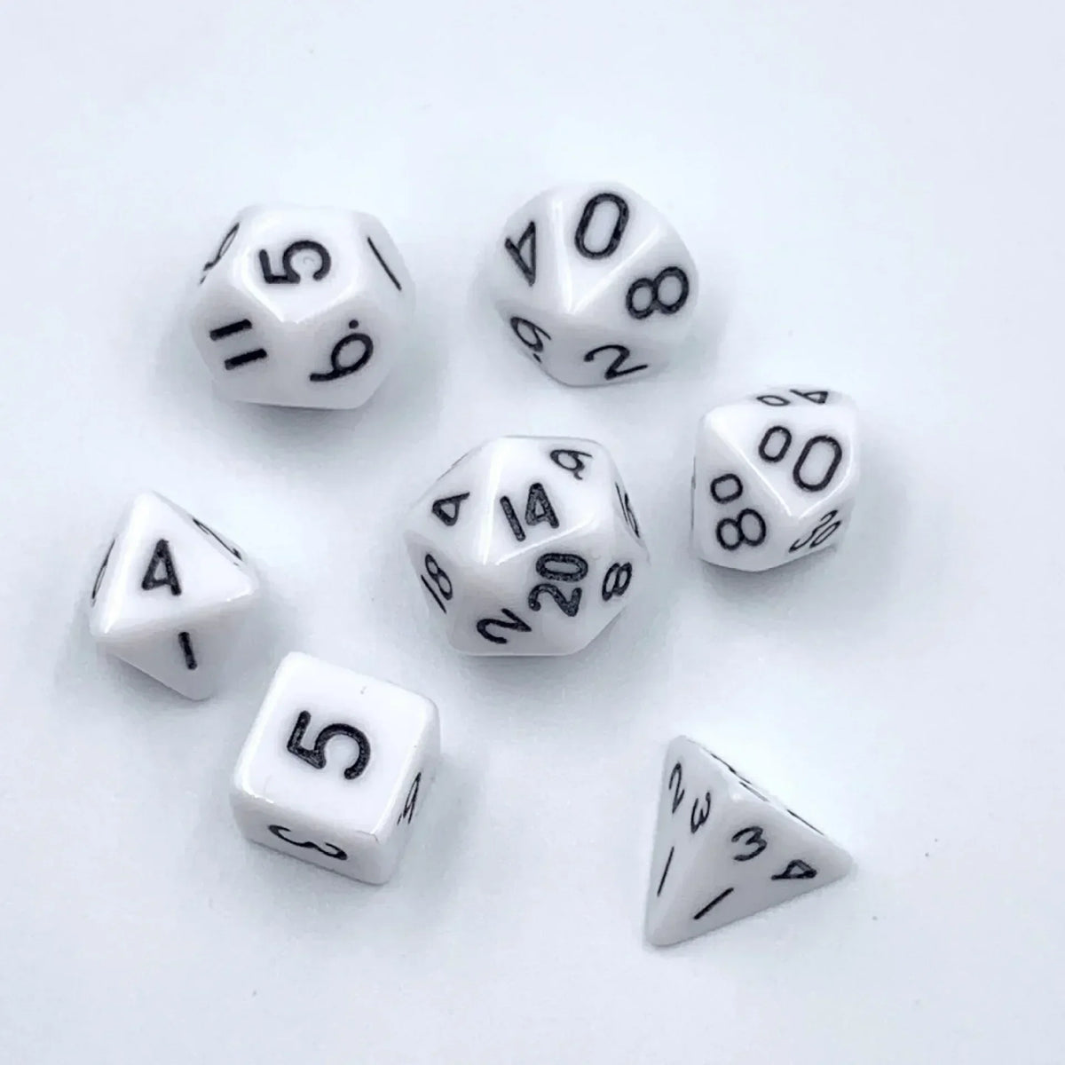 A collection of seven mini polyhedral dice, including d6s and d8s, scattered on a white surface.
