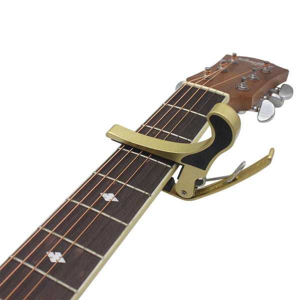 A close-up view of a universal metal guitar capo tuning clamp with a wooden body and metal tuning pegs.