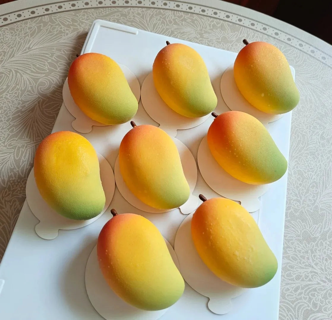 A collection of ripe yellow and orange mangoes displayed on a white platter.