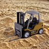 Mini camion forklift télécommandé jaune sur un sol sablonneux avec de petits cailloux.