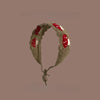 A handmade strawberry crochet headband with a wide elastic band against a solid brown background.