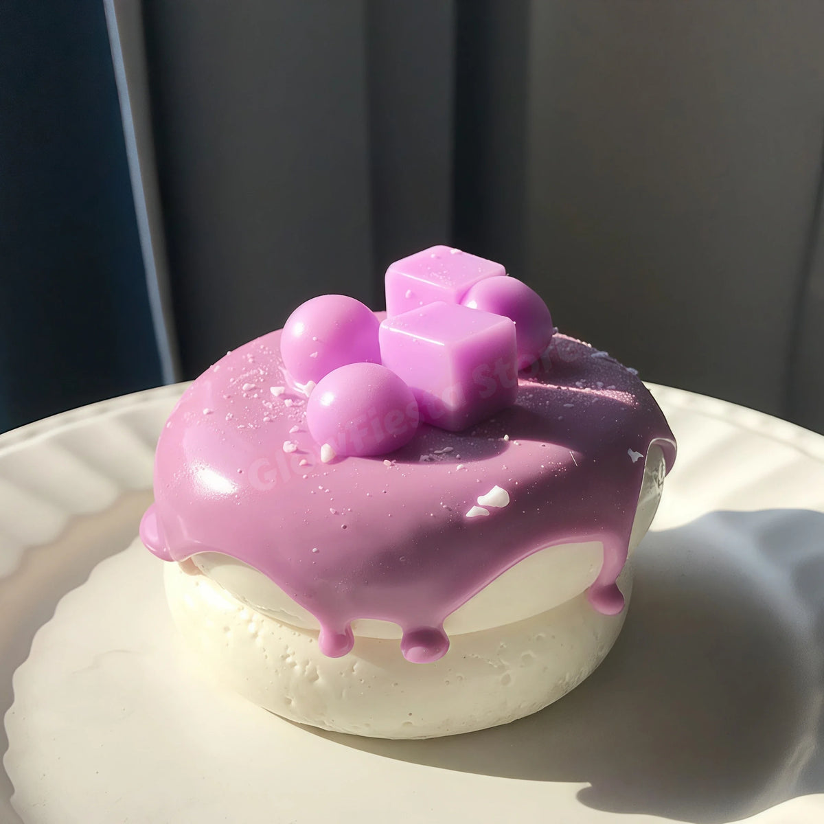 A pink and purple glazed cream puff with small pastel cubes on a white plate.