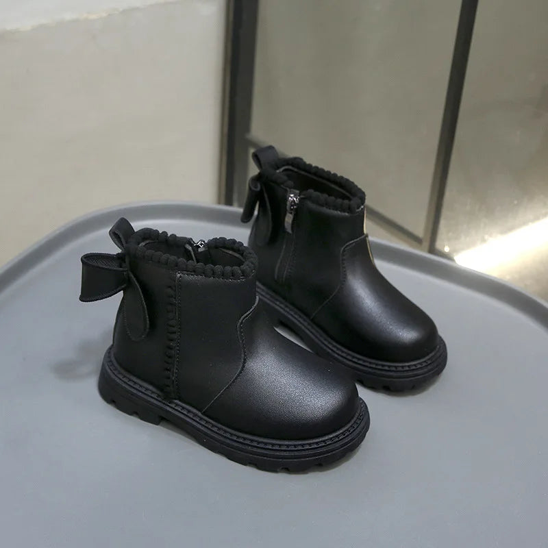 A pair of black faux leather winter boots with a folded cuff displayed on a gray plate.