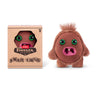 A brown plush monster toy with large green eyes and pink mouth is shown next to its packaging.