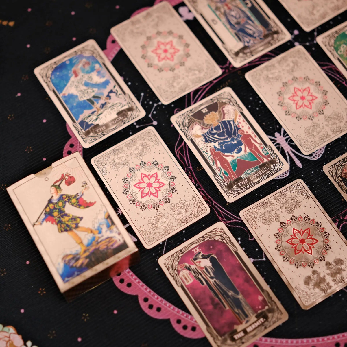 A collection of mini gold foil tarot cards arranged on a dark surface.